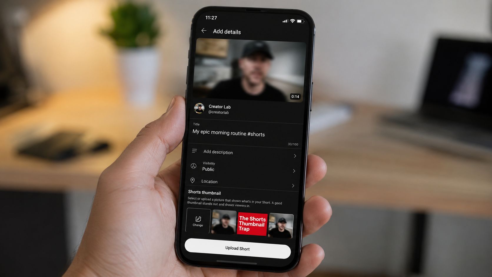 A hand holding a smartphone displaying the YouTube upload details screen for editing a Shorts video thumbnail.